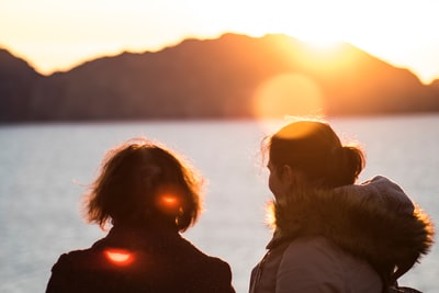 两个人站在海滩上欣赏夕阳